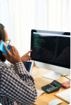 Image of a man talking on the phone while working on the computer