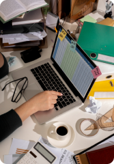 Image of a person working on the laptop with some design utensils on the table